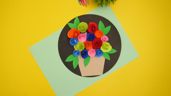 Finished paper roses in a vase craft featuring handmade red roses with green stems and leaves arranged in a decorative paper vase.